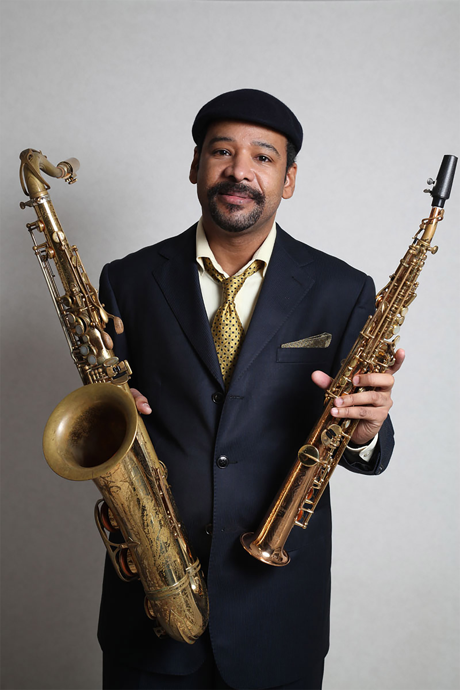 Tony Spruill holding tenor and soprano saxophones during a professional portrait session.